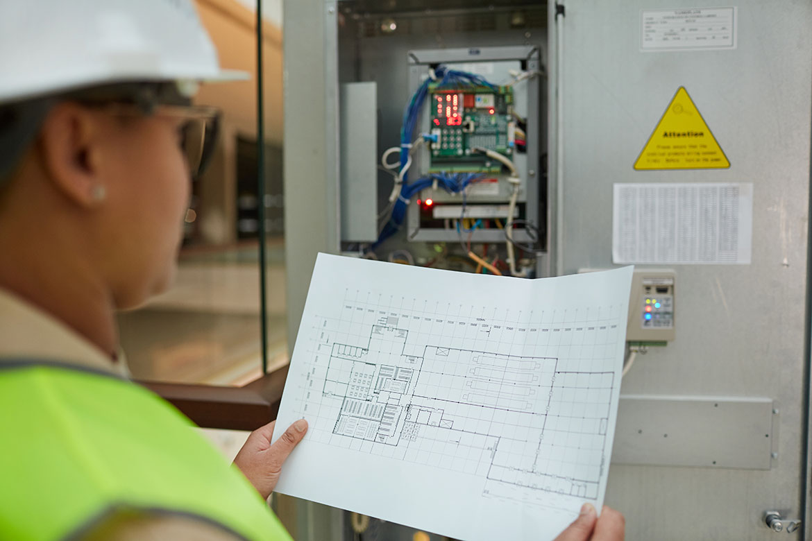 Electrical technician reviewing blueprints during a commercial wiring project.